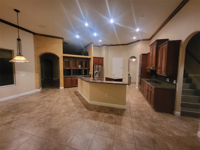 kitchen with arched walkways, gas cooktop, stainless steel refrigerator with ice dispenser, an island with sink, and crown molding