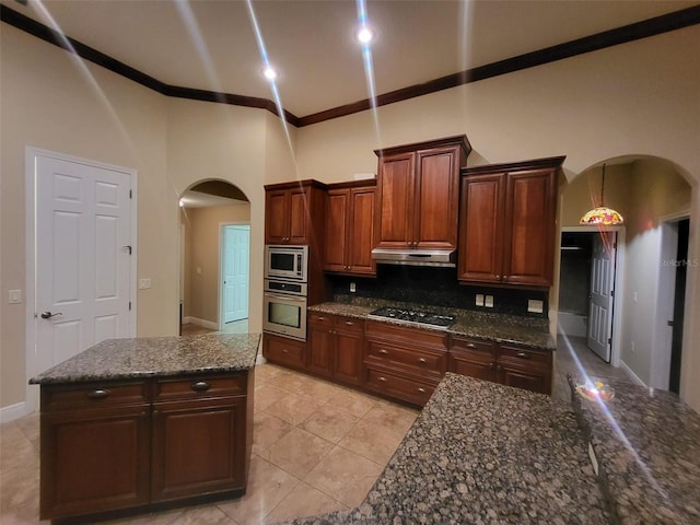 kitchen featuring arched walkways, stainless steel appliances, ornamental molding, and under cabinet range hood