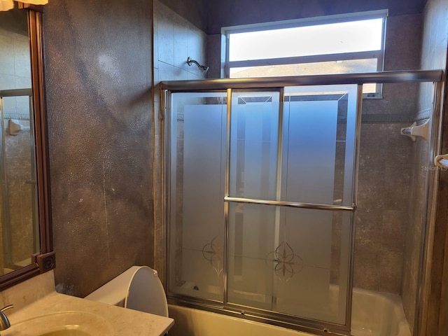 bathroom with combined bath / shower with glass door, vanity, and toilet