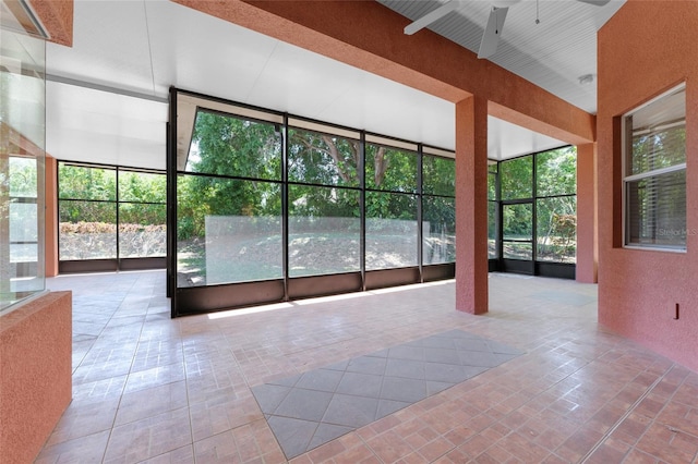 unfurnished sunroom with a ceiling fan and a wealth of natural light