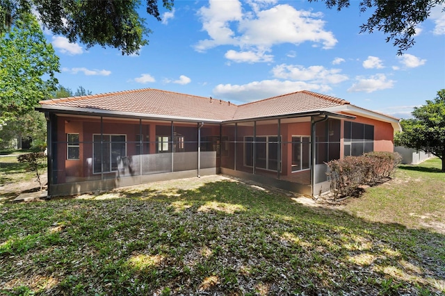 rear view of house featuring a lawn, a tile roof, and a sunroom