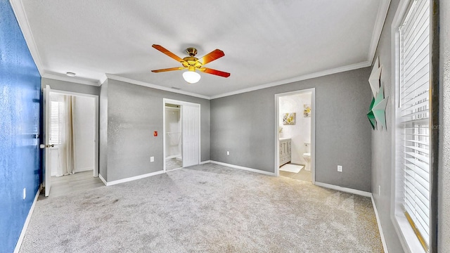 unfurnished bedroom with ensuite bathroom, crown molding, ceiling fan, and light colored carpet