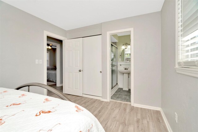 bedroom with ensuite bathroom, light hardwood / wood-style flooring, and a closet