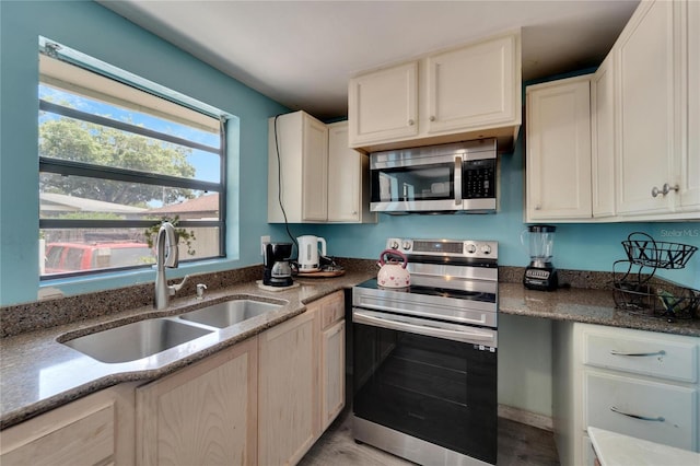 kitchen featuring appliances with stainless steel finishes, sink, stone counters, and light hardwood / wood-style flooring