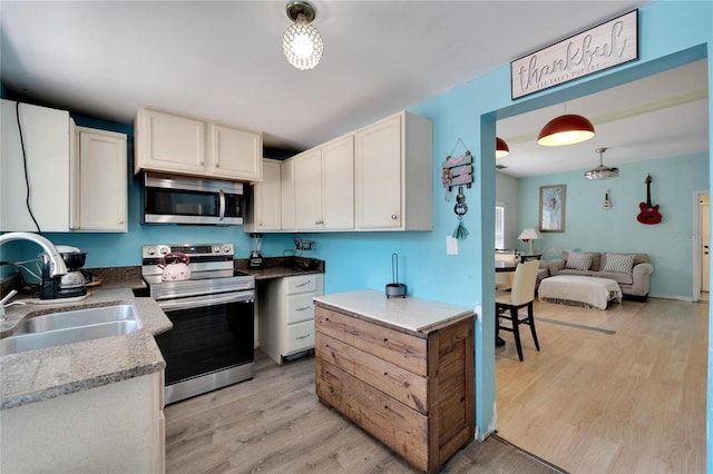 kitchen with decorative light fixtures, sink, light wood-type flooring, and stainless steel appliances