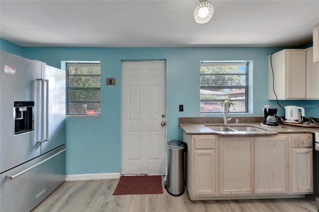 kitchen featuring a healthy amount of sunlight, high end refrigerator, sink, and light wood-type flooring