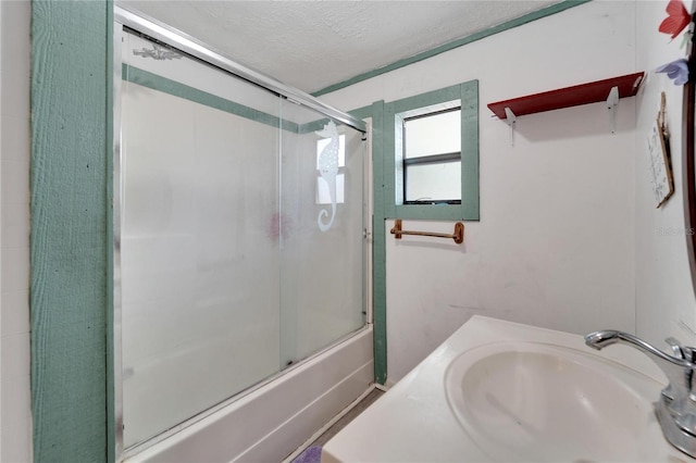 bathroom featuring bath / shower combo with glass door, sink, and a textured ceiling