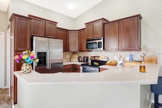 kitchen featuring tasteful backsplash, appliances with stainless steel finishes, and kitchen peninsula