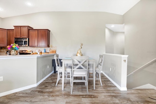 dining area featuring wood-type flooring and vaulted ceiling