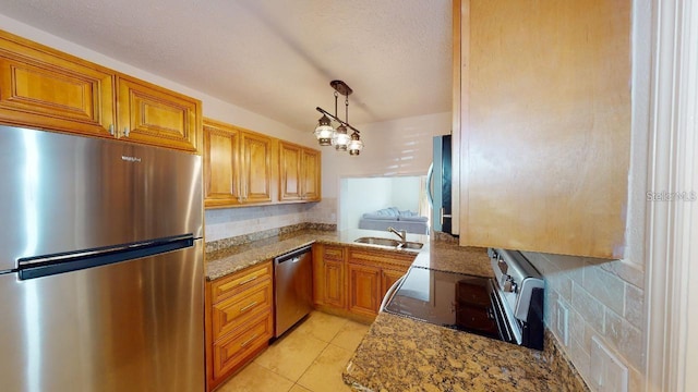 kitchen with decorative light fixtures, tasteful backsplash, dark stone countertops, appliances with stainless steel finishes, and light tile floors