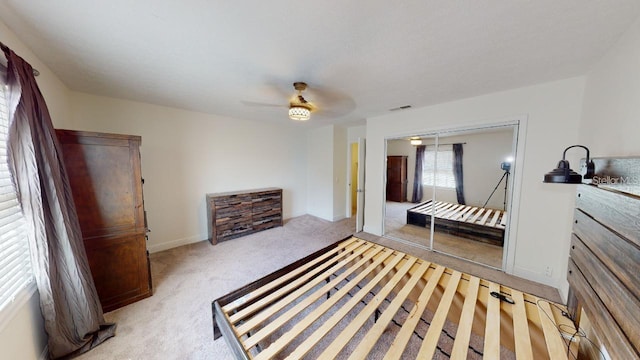 carpeted bedroom with ceiling fan and a closet