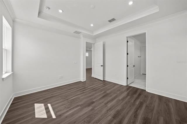 unfurnished bedroom with a tray ceiling, dark hardwood / wood-style floors, and ornamental molding