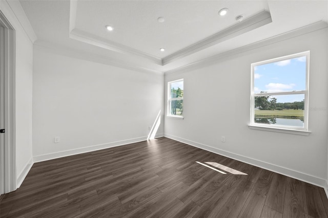 empty room with dark wood-type flooring, a raised ceiling, and ornamental molding