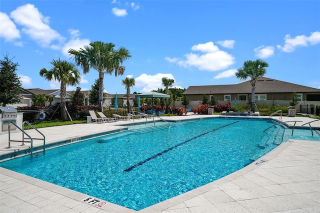 view of swimming pool featuring a patio and grilling area