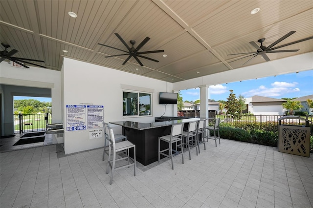 view of patio with area for grilling, ceiling fan, and a bar