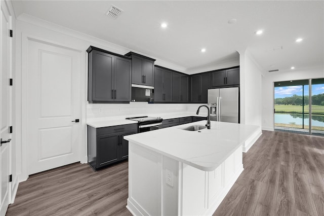 kitchen featuring a kitchen island with sink, crown molding, sink, hardwood / wood-style flooring, and appliances with stainless steel finishes