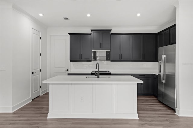 kitchen with a center island with sink, stainless steel fridge with ice dispenser, sink, and hardwood / wood-style flooring