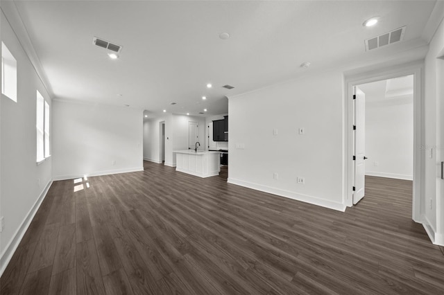 unfurnished living room featuring dark wood-type flooring, crown molding, and sink