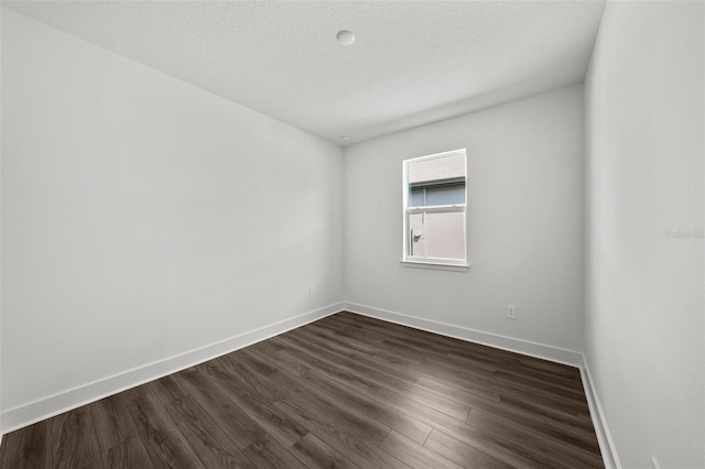 spare room with a textured ceiling and dark hardwood / wood-style flooring