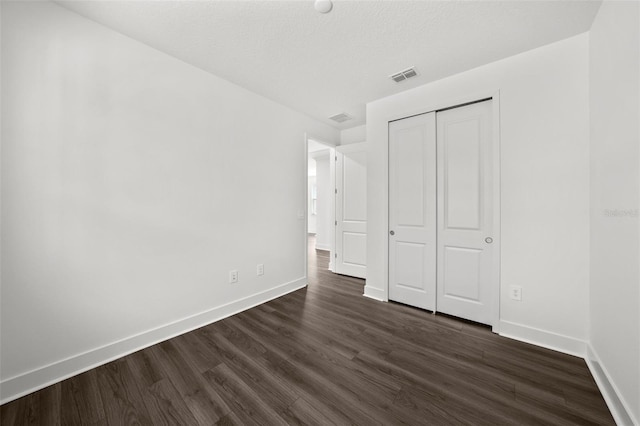 unfurnished bedroom with a closet and dark hardwood / wood-style floors