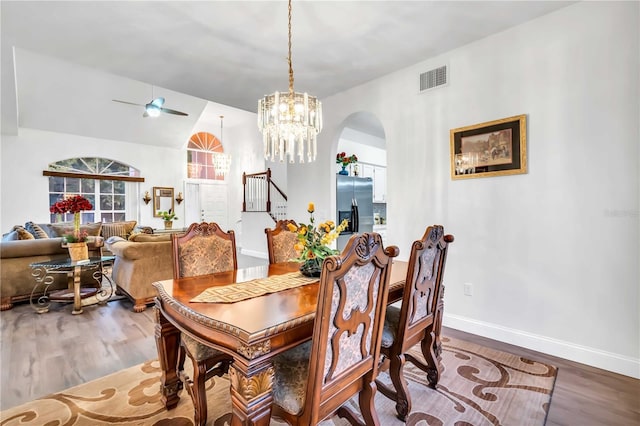 dining room featuring wood finished floors, arched walkways, visible vents, and baseboards