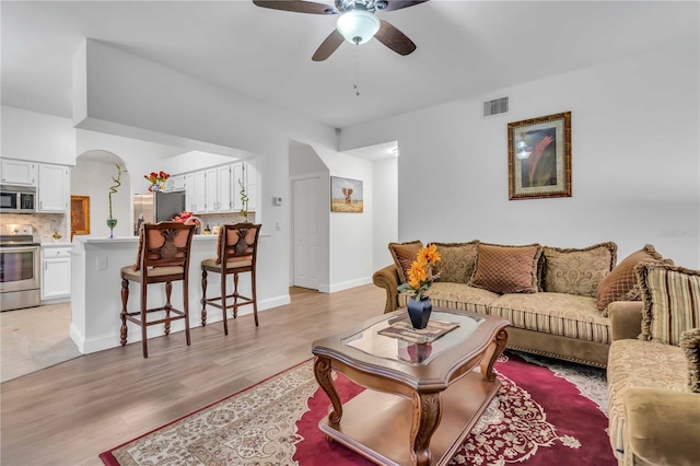living area featuring visible vents, baseboards, light wood-type flooring, and a ceiling fan