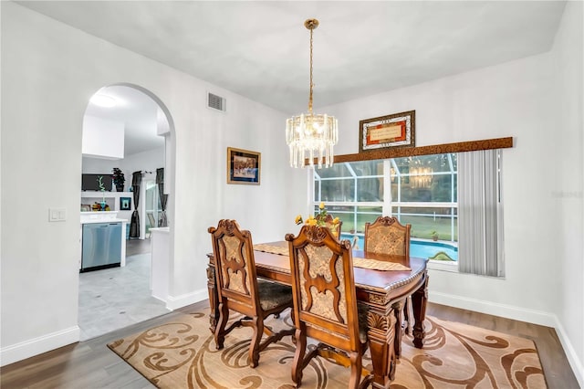 dining space featuring visible vents, wood finished floors, arched walkways, and baseboards