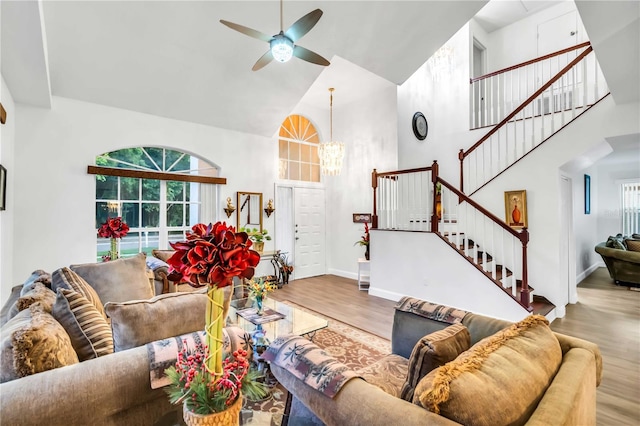 living room with high vaulted ceiling, ceiling fan with notable chandelier, and hardwood / wood-style flooring