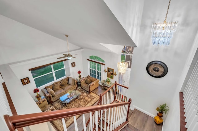 stairway featuring baseboards, lofted ceiling, wood finished floors, and ceiling fan with notable chandelier