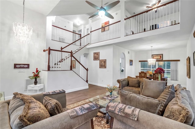 living area featuring visible vents, baseboards, stairs, ceiling fan with notable chandelier, and wood finished floors