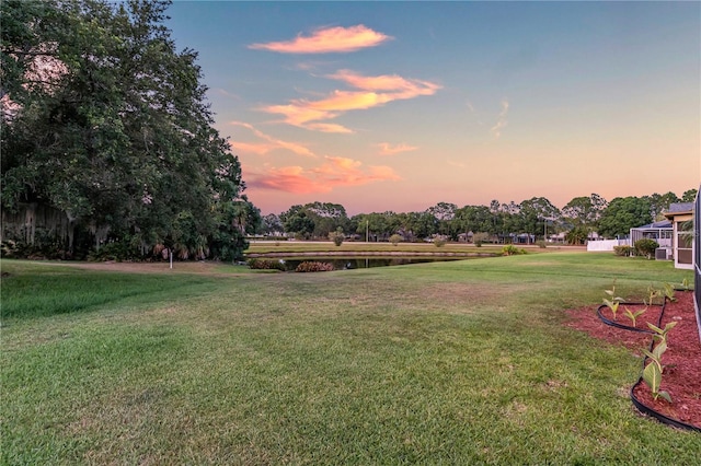 yard at dusk featuring a water view