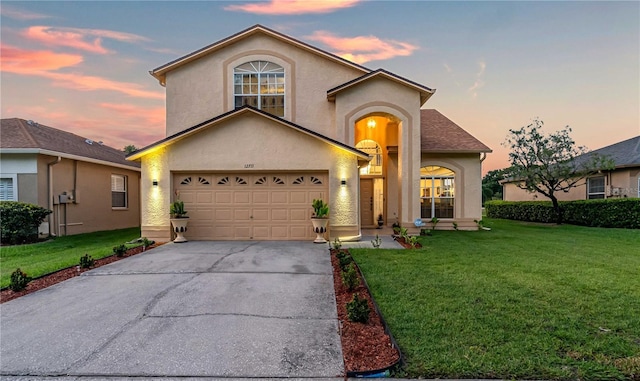 view of front of house with stucco siding, an attached garage, concrete driveway, and a yard