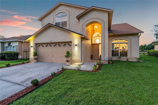 view of front of property with stucco siding, a lawn, and driveway