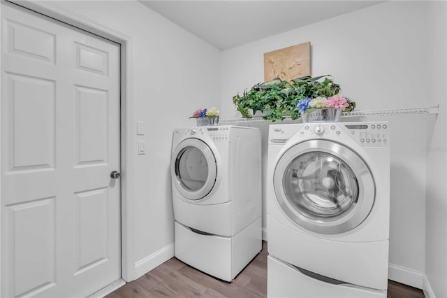 laundry area with washer and dryer, laundry area, wood finished floors, and baseboards