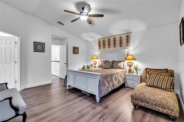 bedroom with visible vents, a ceiling fan, wood finished floors, baseboards, and vaulted ceiling