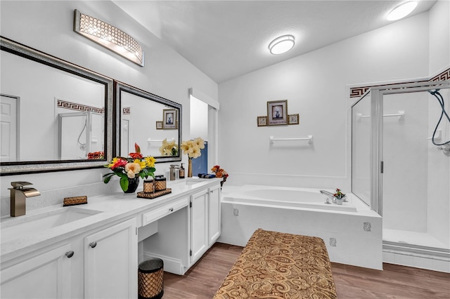 bathroom featuring dual bowl vanity, hardwood / wood-style floors, lofted ceiling, and plus walk in shower