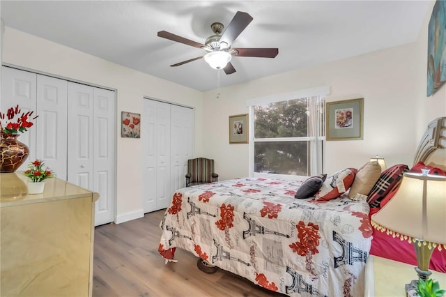 bedroom with hardwood / wood-style flooring, two closets, and ceiling fan