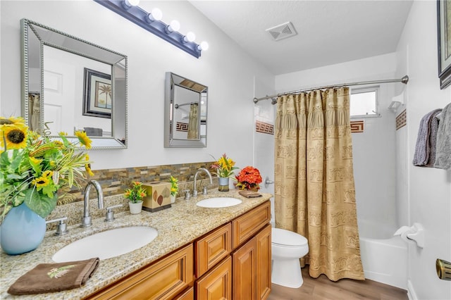 full bathroom featuring vanity with extensive cabinet space, dual sinks, toilet, shower / tub combo, and wood-type flooring