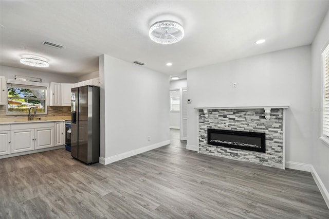 unfurnished living room featuring a fireplace, light hardwood / wood-style floors, and sink