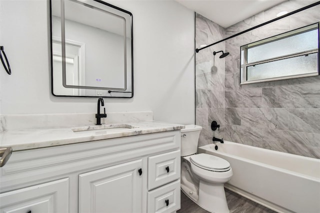 full bathroom featuring hardwood / wood-style floors, vanity, toilet, and tiled shower / bath