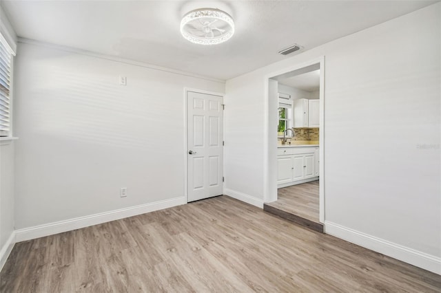 empty room with a wealth of natural light, sink, and light hardwood / wood-style floors