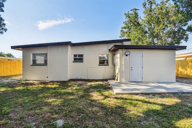 back of property featuring a lawn and a patio