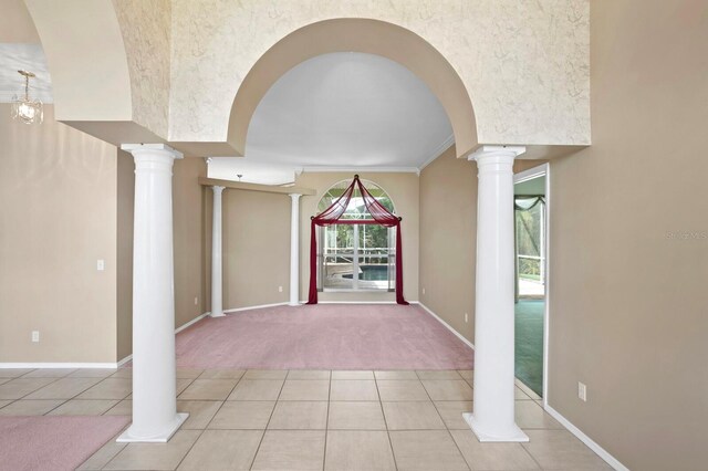 unfurnished living room with ornate columns, light carpet, and crown molding