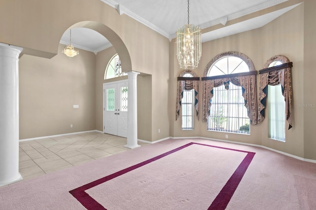 carpeted entryway with an inviting chandelier, crown molding, a towering ceiling, and ornate columns