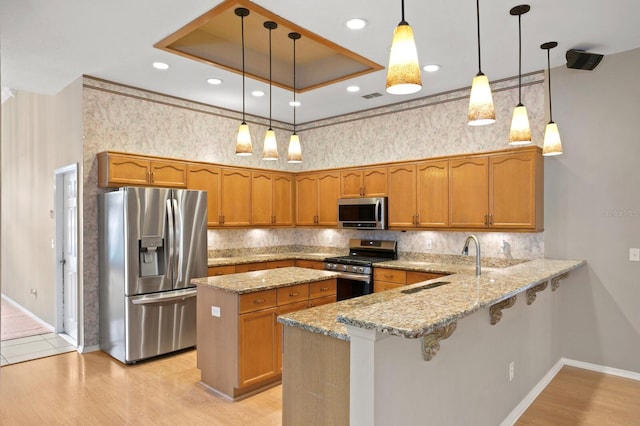 kitchen featuring pendant lighting, sink, appliances with stainless steel finishes, light stone counters, and kitchen peninsula