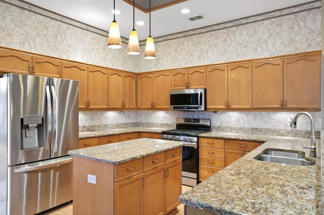 kitchen featuring light stone counters, sink, hanging light fixtures, and appliances with stainless steel finishes