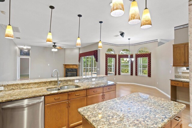 kitchen with light hardwood / wood-style floors, dishwasher, a fireplace, and decorative light fixtures