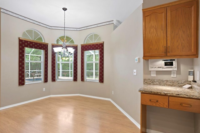 unfurnished dining area featuring an inviting chandelier and light hardwood / wood-style floors