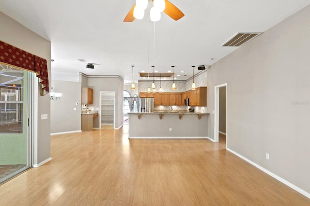 unfurnished living room featuring a healthy amount of sunlight, ceiling fan, and light wood-type flooring