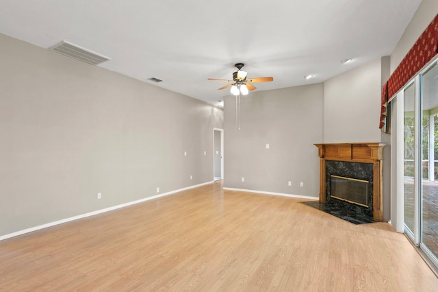 unfurnished living room with a high end fireplace, ceiling fan, and light hardwood / wood-style floors